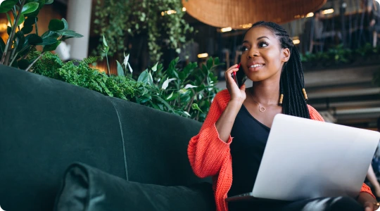 African american woman with phone laptop cafe